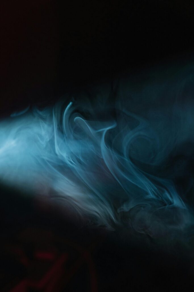 Moody abstract image of swirling blue smoke with dark background and dramatic lighting.